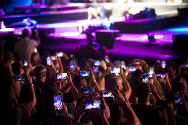 Audience standing on dance floor and recording video of concerts on smartphones during music festival - ADSF44916