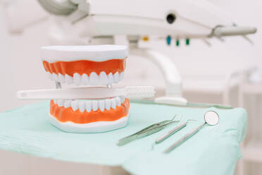 Set of various dental instruments and dentures with toothbrush placed on table in modern dental clinic - ADSF44924