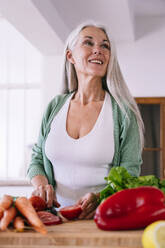 Happy mature woman preparing food in kitchen at home - OIPF03239