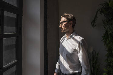 Businessman wearing eyeglasses standing in office with eyes closed - VPIF08277