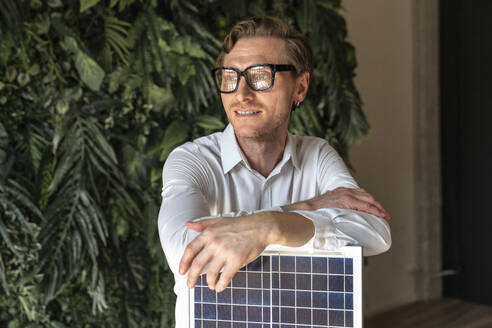 Contemplative businessman with solar panel in office - VPIF08284