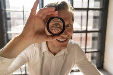 Happy mature businessman looking through magnifying glass - VPIF08298