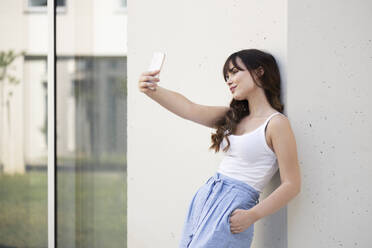 Eine junge Frau nimmt ein Selbstporträt mit der Kamera ihres Smartphones auf - LMCF00346