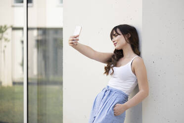 Young woman taking selfie through smart phone - LMCF00346