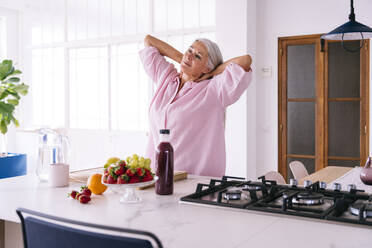 Frau streckt sich in der Küche zu Hause - OIPF03302