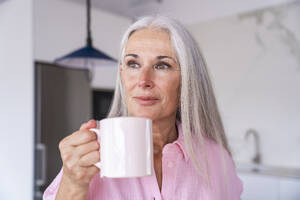 Kontemplative reife Frau hält Kaffeetasse zu Hause - OIPF03308