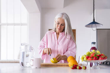 Mature woman cutting lemon in kitchen at home - OIPF03314