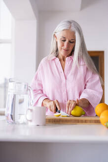 Frau schneidet Zitrone in der Küche zu Hause - OIPF03315