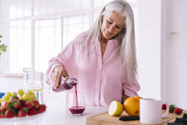 Ältere Frau gießt gesunden Saft in ein Glas zu Hause - OIPF03340