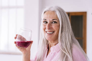 Glückliche Frau hält Glas mit gesundem Saft zu Hause - OIPF03341