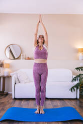 Woman doing yoga with hands clasped standing at home - OIPF03373