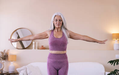Woman exercising with arms outstretched at home - OIPF03374