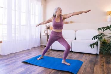 Frau macht Dehnungsübungen auf Yogamatte zu Hause - OIPF03376