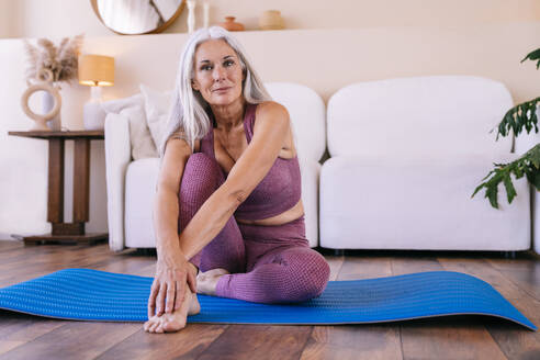 Frau sitzt auf Yogamatte zu Hause - OIPF03384