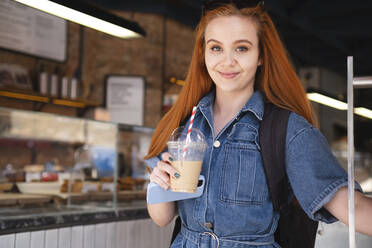 Smiling businesswoman holding coffee and smart phone in cafe - AMWF01461