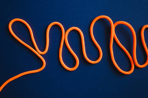 From above of arrange orange shoelaces in mess on blue background - ADSF44970