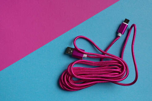 Top view of neon pink colored USB cable on colorful cardboard background - ADSF44985