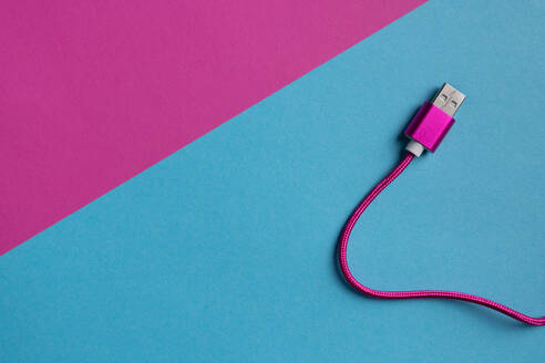 Top view of neon pink colored USB cable on colorful cardboard background - ADSF44986