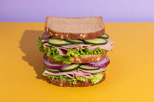 Delicious sandwich with tomatoes, cheese slices and fresh vegetables on colorful background - ADSF45064