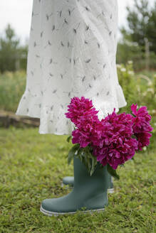 Girl standing with flowers in rubber boot - LESF00341