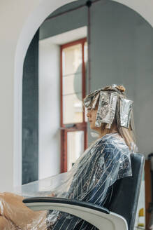 Young woman sitting on chair at salon - VSNF01144