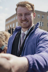 Smiling businessman doing handshake at street - AMWF01480