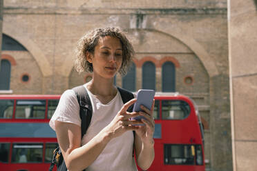 Businesswoman using smart phone in front of building - AMWF01501