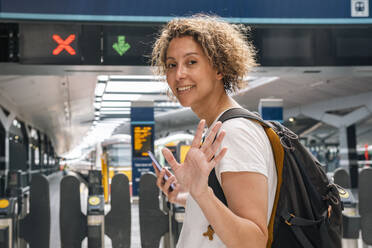 Geschäftsfrau winkt am Bahnhof - AMWF01503