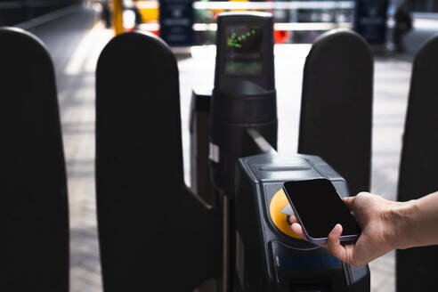Geschäftsfrau scannt Drehkreuz mit Smartphone am Bahnhof - AMWF01505