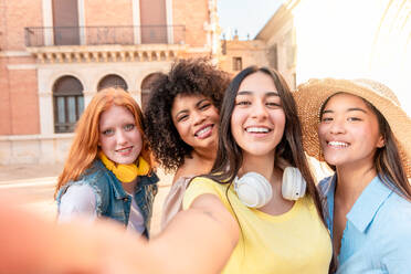 Eine Gruppe von Frauen posiert fröhlich für ein Selfie in einer Straße in Valencia, wobei eine Freundin das Smartphone hält - ADSF45116