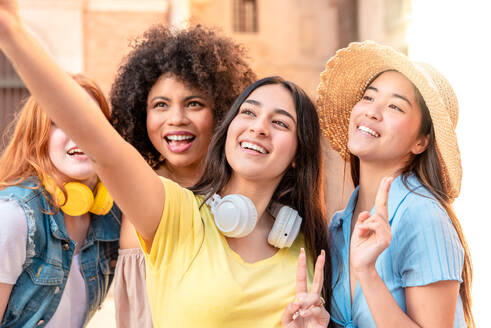Eine Gruppe von Frauen posiert fröhlich für ein Selfie in einer Straße in Valencia, wobei eine Freundin das Smartphone hält - ADSF45117