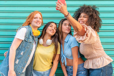 Eine bunte Gruppe modischer Frauen posiert für ein Selfie vor einer grünen Wand in den Straßen von Valencia - ADSF45136