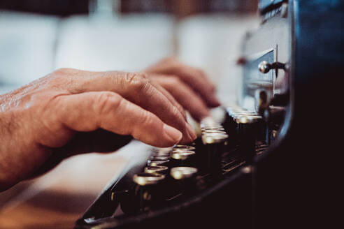 Shot of hands of anonymous elderly person typing on keyboard of vintage typewriter - ADSF45188