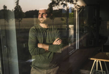 Man with arms crossed seen through glass - UUF29397