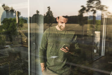Mann mit Smartphone durch Glas gesehen - UUF29401