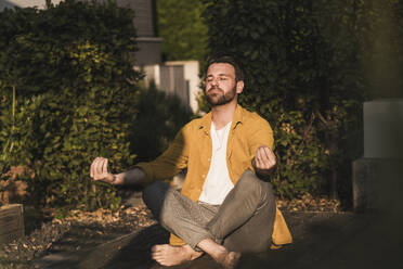 Man practicing yoga on porch - UUF29432