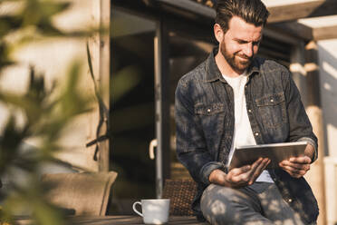 Smiling man using tablet PC on sunny day - UUF29457