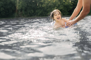 Fröhlicher Junge, der mit seinem Vater im Fluss schwimmen lernt - ANAF01741