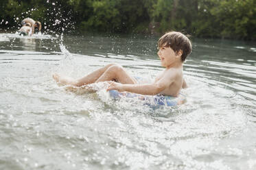 Fröhlicher Junge schwimmt im Wasser mit aufblasbarem Schwimmring - ANAF01751