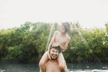 Cheerful father carrying son on shoulders and having fun in river - ANAF01752