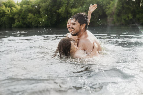 Cheerful father having fun with sons in water - ANAF01754