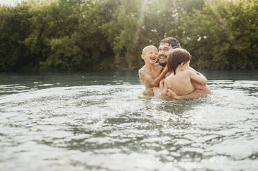 Happy father enjoying with sons in water - ANAF01755