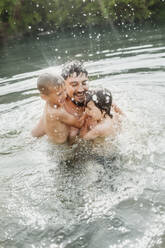 Cheerful father swimming with sons and enjoying in water - ANAF01756