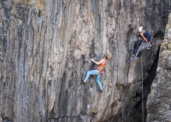 Mann fotografiert Frau beim Bergsteigen mit Seil - ALRF02094