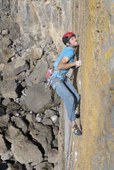 Determined man climbing rocky mountain at sunny day - ALRF02099