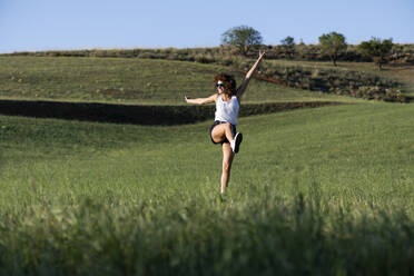 Cheerful woman jumping an dancing in summer meadow - LMCF00392