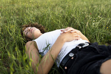 Woman with eyes closed lying on grass - LMCF00404