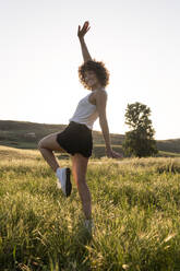 Cheerful woman jumping an dancing in summer meadow - LMCF00405