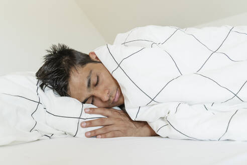 Young man wrapped in blanket sleeping at home - OSF01869