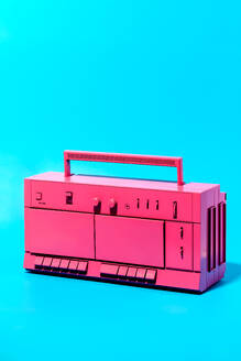 Close-up viewing of bright pink retro cassette tape recorder placed in studio against blue background - ADSF45204